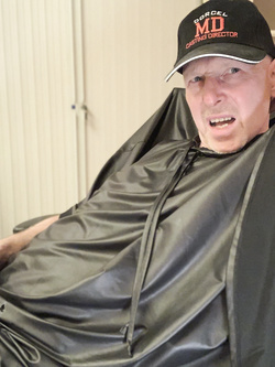 Lenny52, seduto nudo sulla poltrona di pelle nera della sua scrivania, ha indossato l'abito sintetico del parrucchiere.